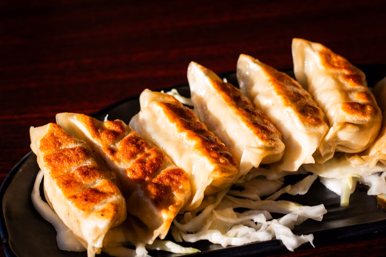 Golden pan-fried gyoza served on a black plate