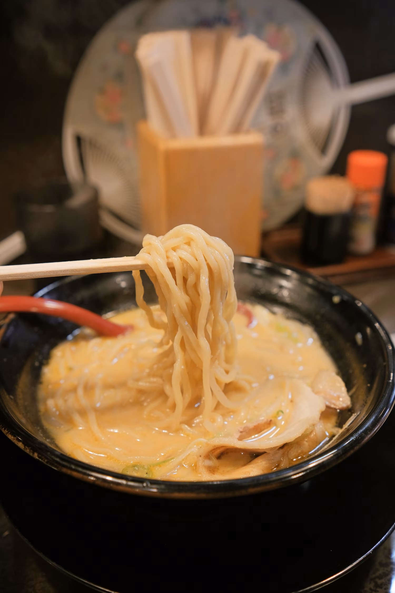Chopsticks lifting noodles from a bowl of ramen