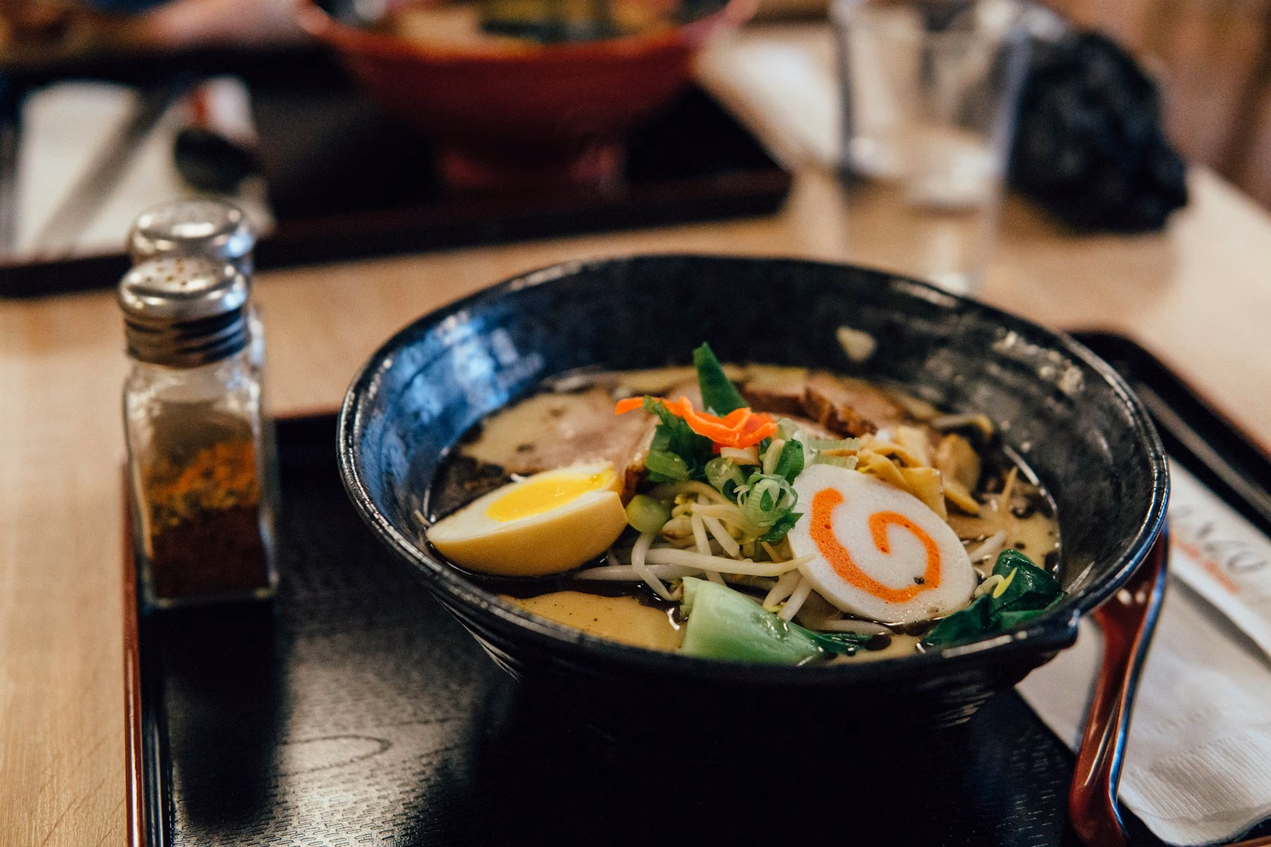A bowl of ramen with noodles, vegetables and lemon